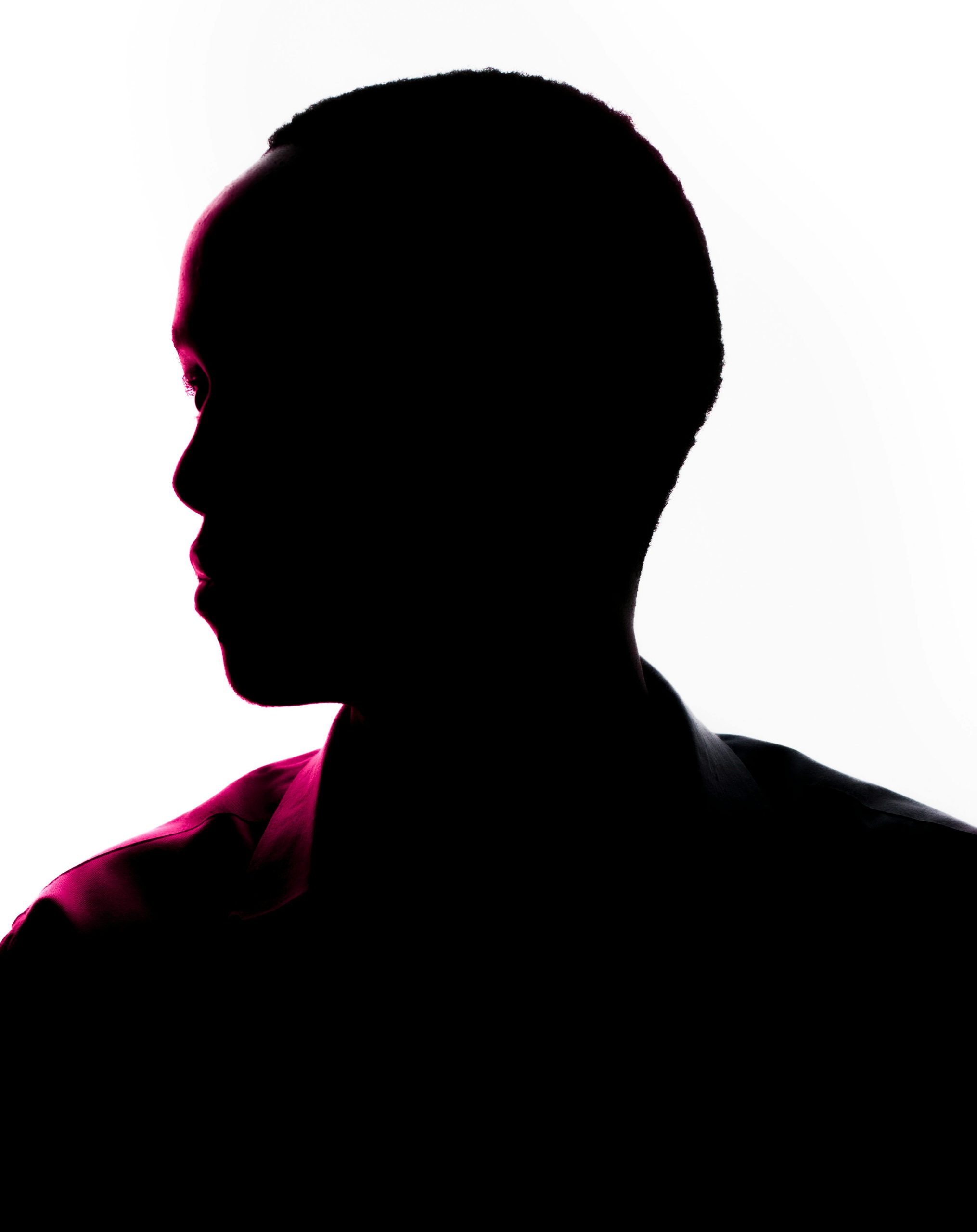 Artistic silhouette portrait featuring pink lighting on a white background.