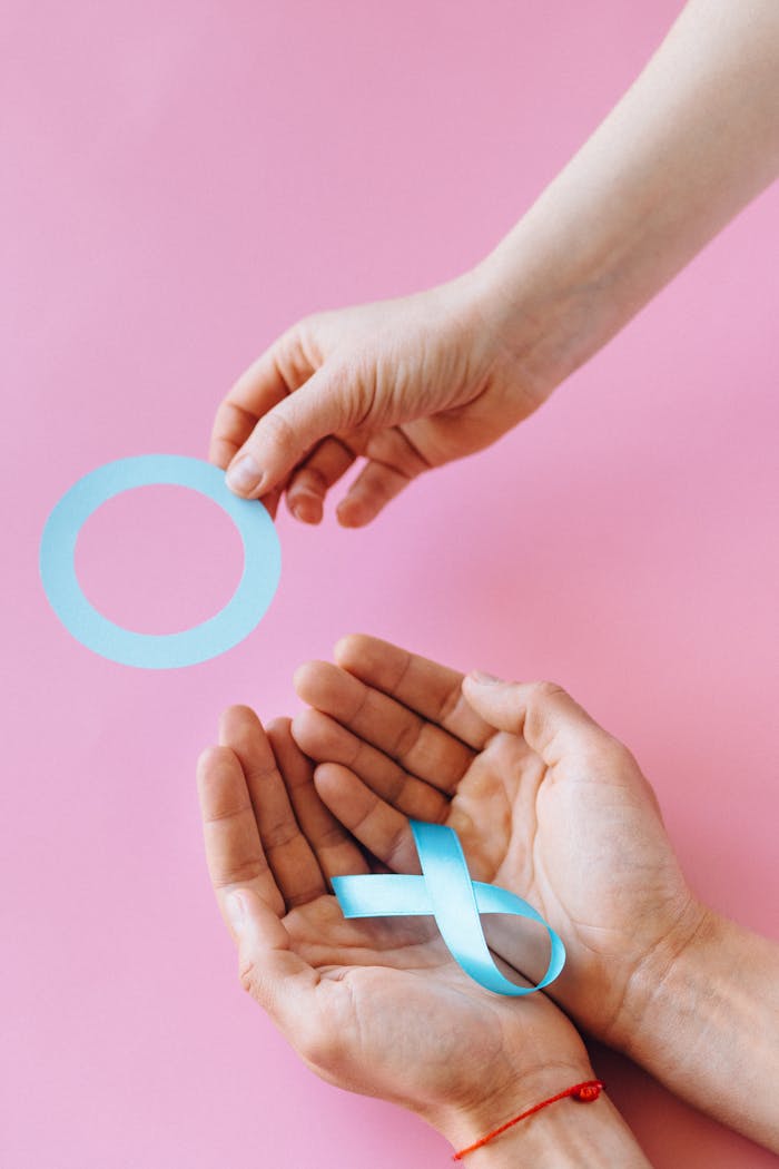 An artistic photo of hands holding a diabetes awareness ribbon on a vibrant pink background.